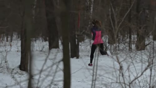 Athletic Woman Jogging Through Forest in Winter