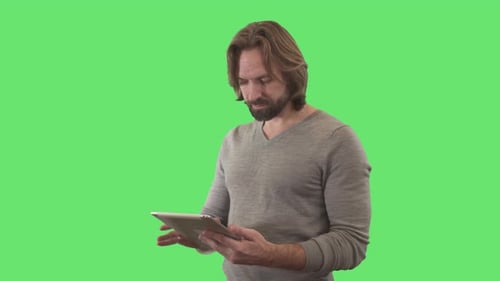 Concentrated Young Man Using Tablet and Smiling at Camera. Portrait of Caucasian Businessman Using