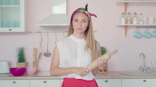 Woman Holding Rolling Pin in Pink Kitchen