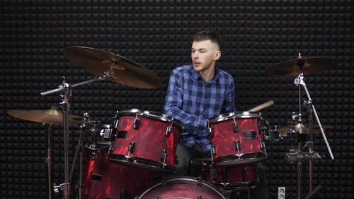 Musician drummer is playing on drum kit on stage at sound recording studio