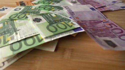 Euro Banknotes Falling onto a Wooden Surface