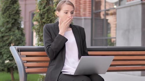 Businesswoman Reacts with Surprise While Working on Laptop
