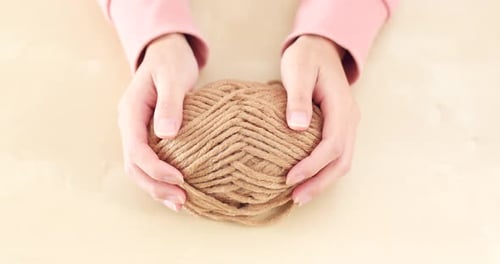 Hands Shaping Ball of Tan-Colored Twine