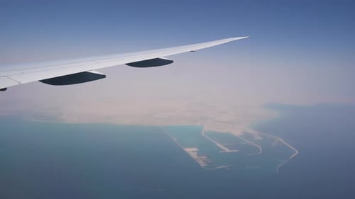 the Plane Flies at High Altitude. View From the Window on the Wing. Turquoise Water Under the Wing
