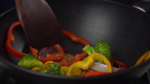 Cook frying various vegetables in pan
