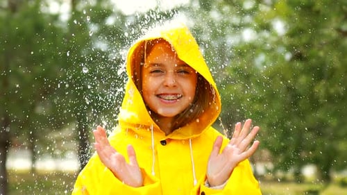 Girl in Raincoat Enjoys Playing in the Rain