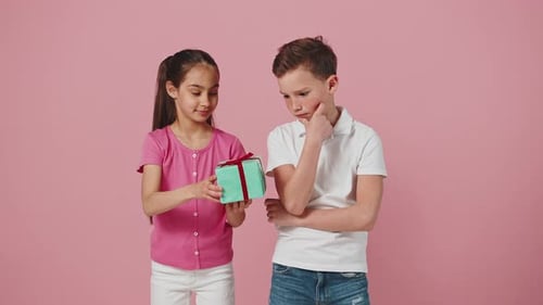 Cute Little Girl Giving Gift Box to Brother Greeting Him with Holiday Boy Shaking Box and Enjoying