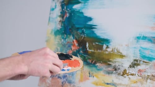 Close Up Shot of the Hand of a Male Artist Holding a Brush and Painting an Oil Painting
