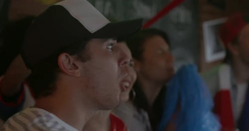 Sports enthusiasts shouting and cheering while watching match in bar, slow motion