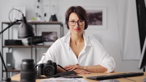 Woman Smiles at Camera at Desk with Equipment