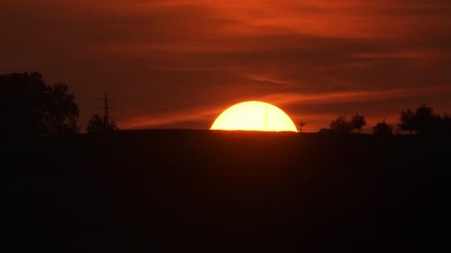 Fiery Sunset Over Rural Tree Lined Horizon