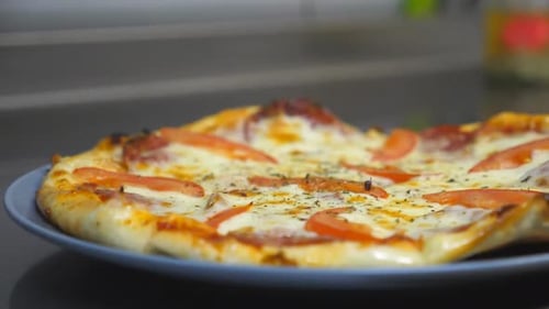 Close Up of Tasty Pepperoni Pizza with Salami Tomato and Cheese in Plate on Wooden Surface at