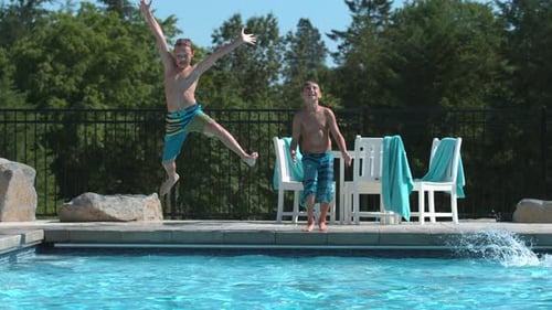 Two boys jumping into pool in super slow motion