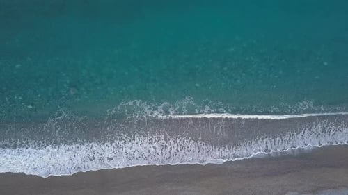 Top Down View Turquoise Waves Reaching Shore Break on Empty Pebble Beach. Pure Sea From Bird's Eye