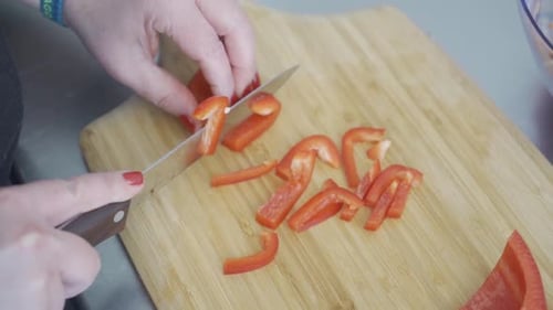 Slicing Red Bell Pepper with Knife on Board