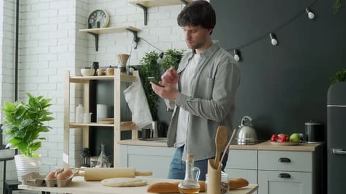 Man Using Phone in Kitchen Preparing Food