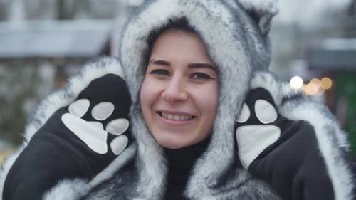 Visage rapproché d'une jeune fille caucasienne souriante portant un chapeau d'animal en fourrure et des gants regardant la caméra.
Portrait