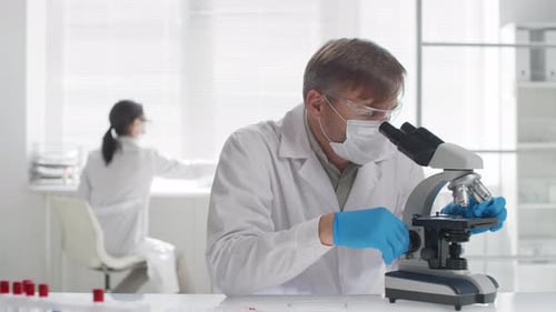 Scientist Works With Microscope in Bright Laboratory