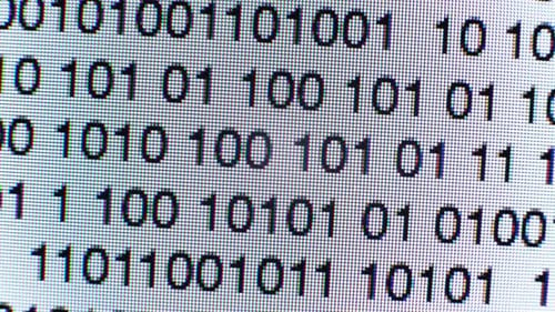 Binary Code Streaming on Computer Screen Close Up