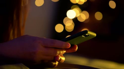 Mujer asiática con teléfono inteligente en la cama por la noche.