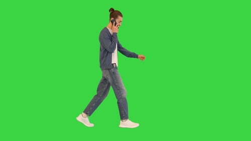 Young White Man Walks Talking on His Smartphone and Smiling on a Green Screen Chroma Key