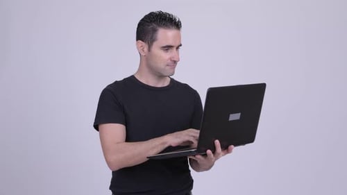 Man Holding and Typing on a Laptop