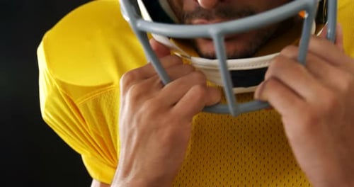 Football Player Putting on Helmet Close Up