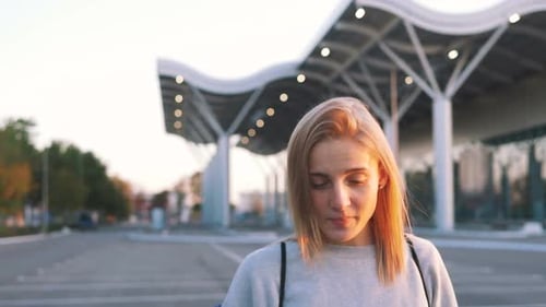 Smiling Woman Poses Outside Airport at Sunset