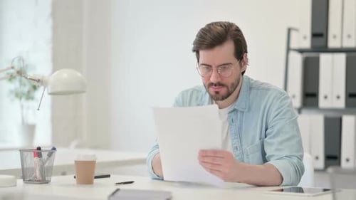 Man Reads Document, Celebrates Success in Office