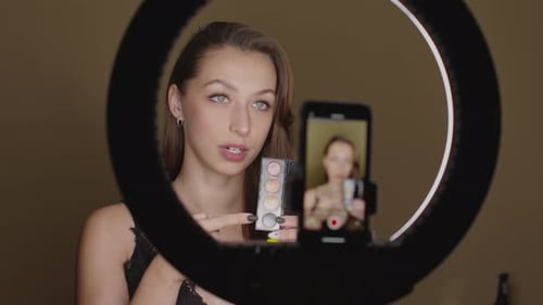 Atractiva bloguera revisando productos cosméticos, maquillaje en vivo