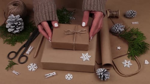 Woman packing Christmas gifts in brown paper