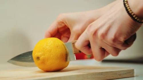 Hände mit Messer Zitronen schneiden auf dem Küchenbrett