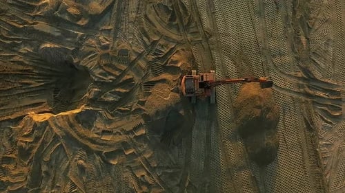 Bagger gleicht Sandoberfläche auf der Baustelle bei Sonnenuntergang aus