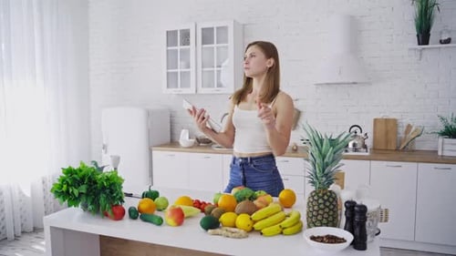 Woman Using Tablet With Fresh Produce in Kitchen