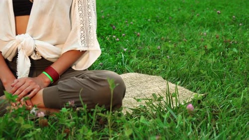 La jeune femme est assise sur le tapis et fait du yoga