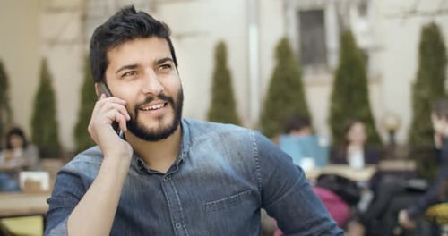 Smiling Young Man Talking on Phone at Cafe