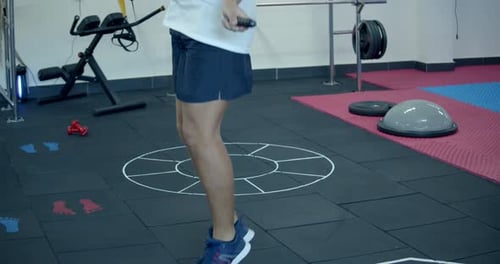 Legs of Male Boxer with Skipping Rope. Fighter Doing Jump Rope Exercises in Dark Gym. Warming Up and