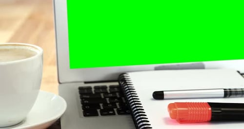 Laptop with Green Screen on a Wooden Desk