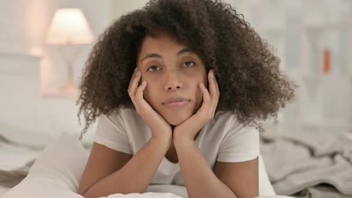 Woman Resting Head in Hands on Bed