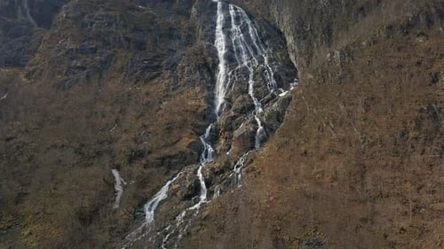 Aerial Tilt Up Aufnahme eines unglaublichen Wasserfalls, der in Norwegen einen Berg hinunterstürzt, während der Schnee schmilzt