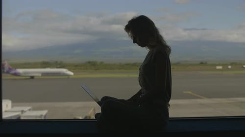 Woman Using Laptop at Airport Terminal
