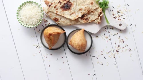 Traditioneller indischer Snack Samosa serviert in einem Teller auf einem weißen Holztisch