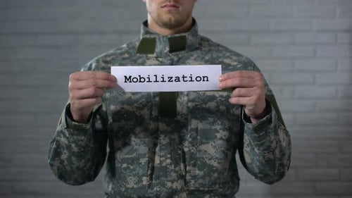 Mobilisierungswort auf Schild in männlichen Soldatenhänden geschrieben, Vorbereitung auf den Krieg