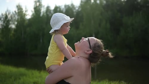 Adult Holding Infant Outside by Grassy Field