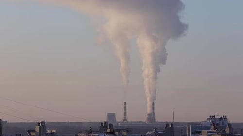 Industrial Smokestacks Emitting Plumes Over Cityscape