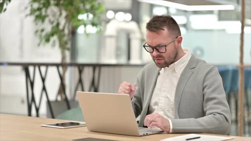 Frustrated Man Working on Laptop in Office
