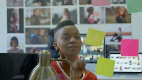 Young Adult Writes on Sticky Notes in Workplace