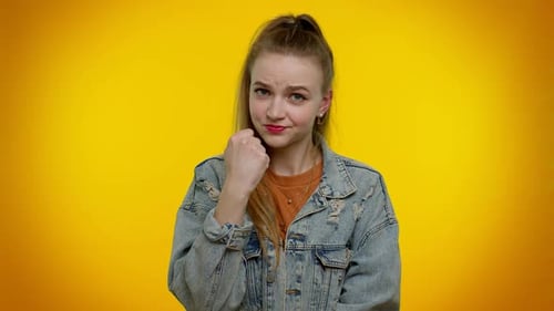 Serious Woman Poses with Fists on Yellow Background
