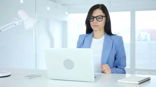 Woman Working on Laptop in Office, Looking Stressed