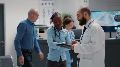 Doctor Consults Patient Using Tablet in Hospital Lobby